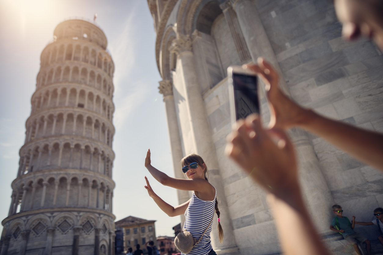 holding up photos of the Leaning Tower of Pisa
