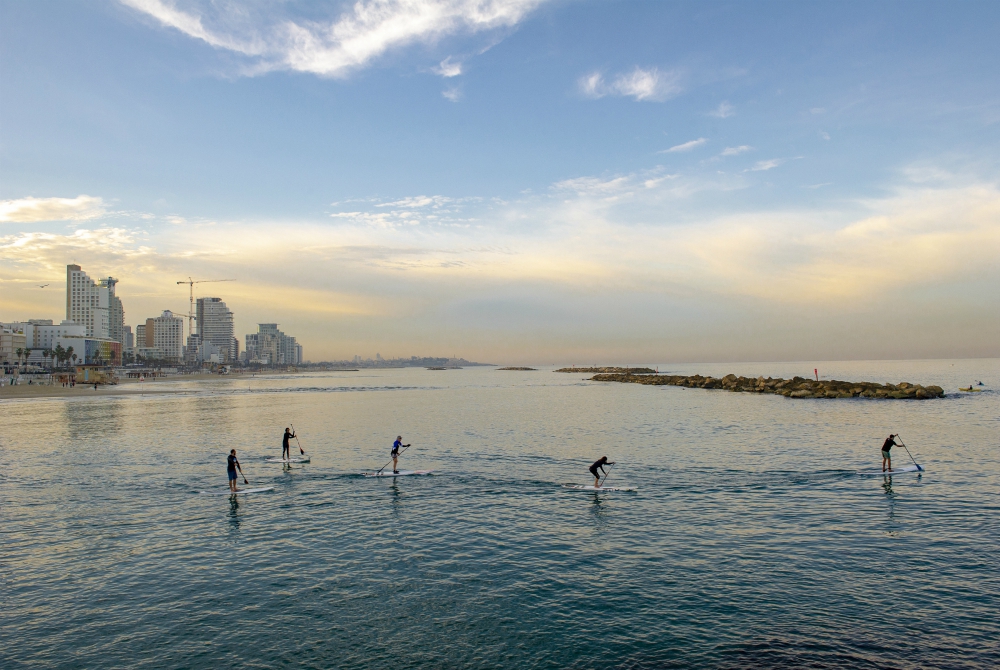 Il Tayelet di Tel Aviv si anima fin dalle prime ore del mattino, con i locali che vi praticano ogni tipo di sport - qui, un piccolo gruppo che pratica Stand Up Paddling