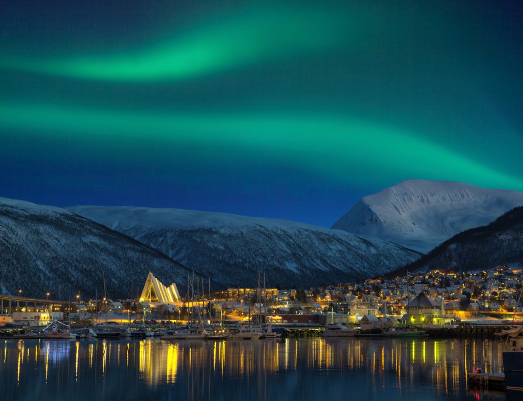 città illuminata di Tromso con cattedrale e maestosa aurora boreale