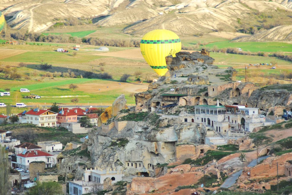 Mongolfiera in volo dietro la città di Cavusin in Cappadocia